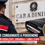 Carabiniere di spalle davanti a una caserma con tre portafogli appoggiati su un tavolo durante un’inchiesta a Pordenone