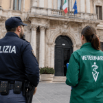 Poliziotto e veterinario davanti a un palazzo istituzionale durante un controllo ufficiale
